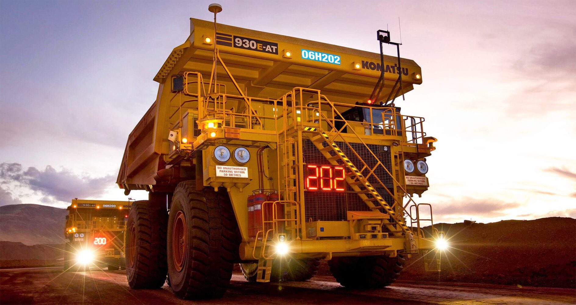 Komatsu 930E-AT autonomous haul trucks operating in a controlled mining haulage environment at dusk